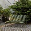 Grüne HAY Palissade Gartenbank aus Metall im modernen Design, platziert auf gepflastertem Boden neben üppigen Pflanzen. - Palissade Dining Gartenbank