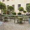 Grüne HAY Palissade Gartenmöbel aus Metall in einem gepflasterten Innenhof umgeben von Pflanzen und Bäumen. - Palissade Gartenstuhl 4er Set