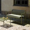 Grüne HAY Palissade Gartenbank aus Metall mit Kissen im Freien, zwei passende Tassen auf Tisch, gepflasterten Untergrund. - Palissade Dining Gartenbank